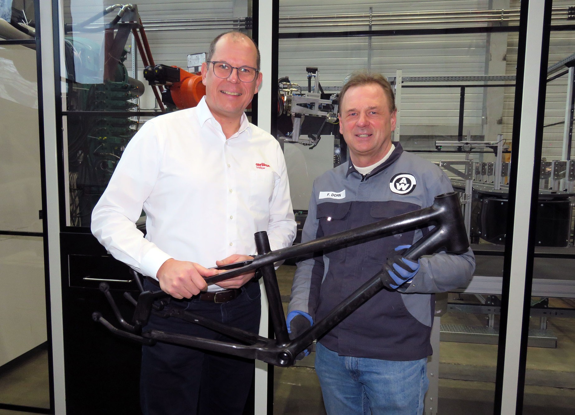 Felix Dorn of Weber Fibertech, right, and Joachim Scheffer of Oerlikon HRSflow, presenting a frame for the li:on youth bicycle that was injection-molded using water injection technology and FLEXflow HRS servo-driven hot runner technology. © Oerlikon HRSflow